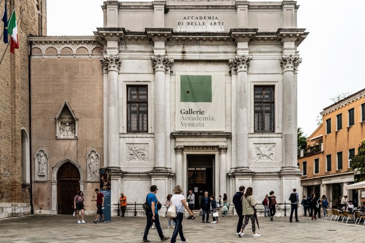 People walking in front of a historic building with columns and a sign reading 'Gallerie Accademia, Venezia'.