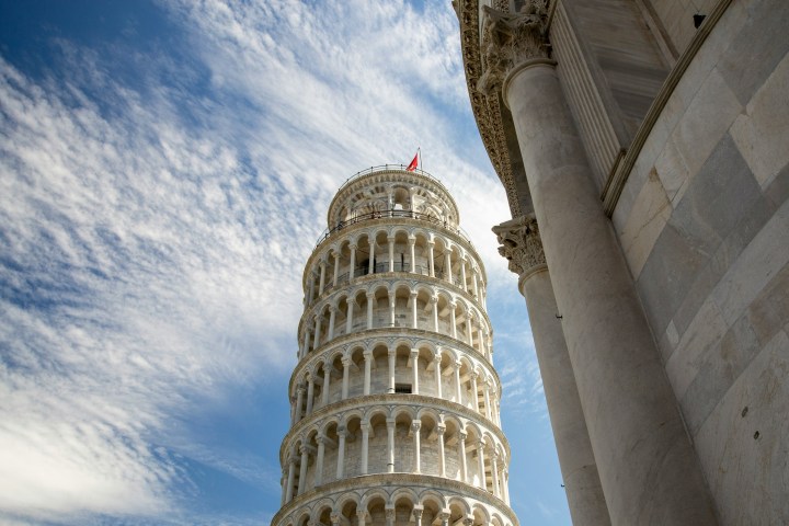 View of the Leaning Tower of Pisa with blue sky and clouds in the background.