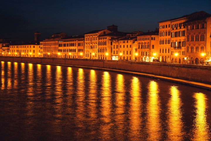 Night view of river with brightly lit buildings reflecting on water.