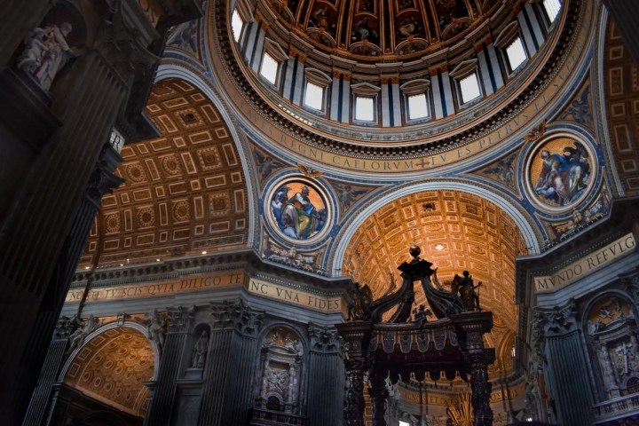 Interior of St. Peter's Basilica with ornate dome, sculptures, and intricate architecture.
