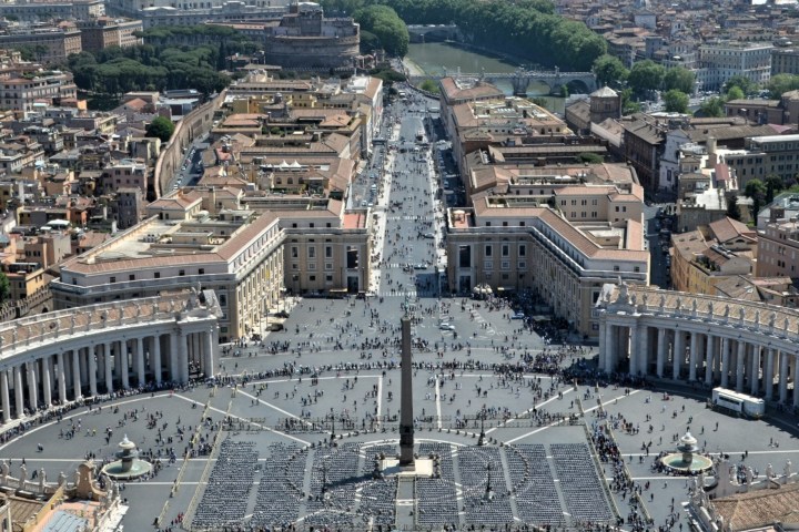 Aerial view of St. Peter's Square, Rome with obelisk and crowds, flanked by colonnades.